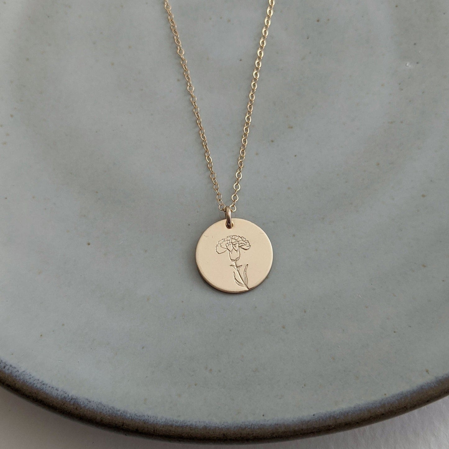 gold disc with carnation flower january birthflower